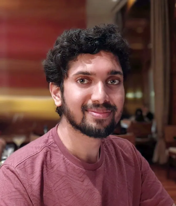 Siddhesh Sali, photographed indoors against a warmly lit interior, looking towards the camera.